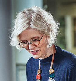 June Williamson smiles while looking down, dressed in a navy long sleeve shirt.