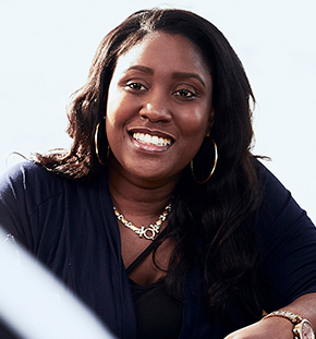 Headshot of Taida Sanvil, dressed in a black shirt, smiling at the camera.