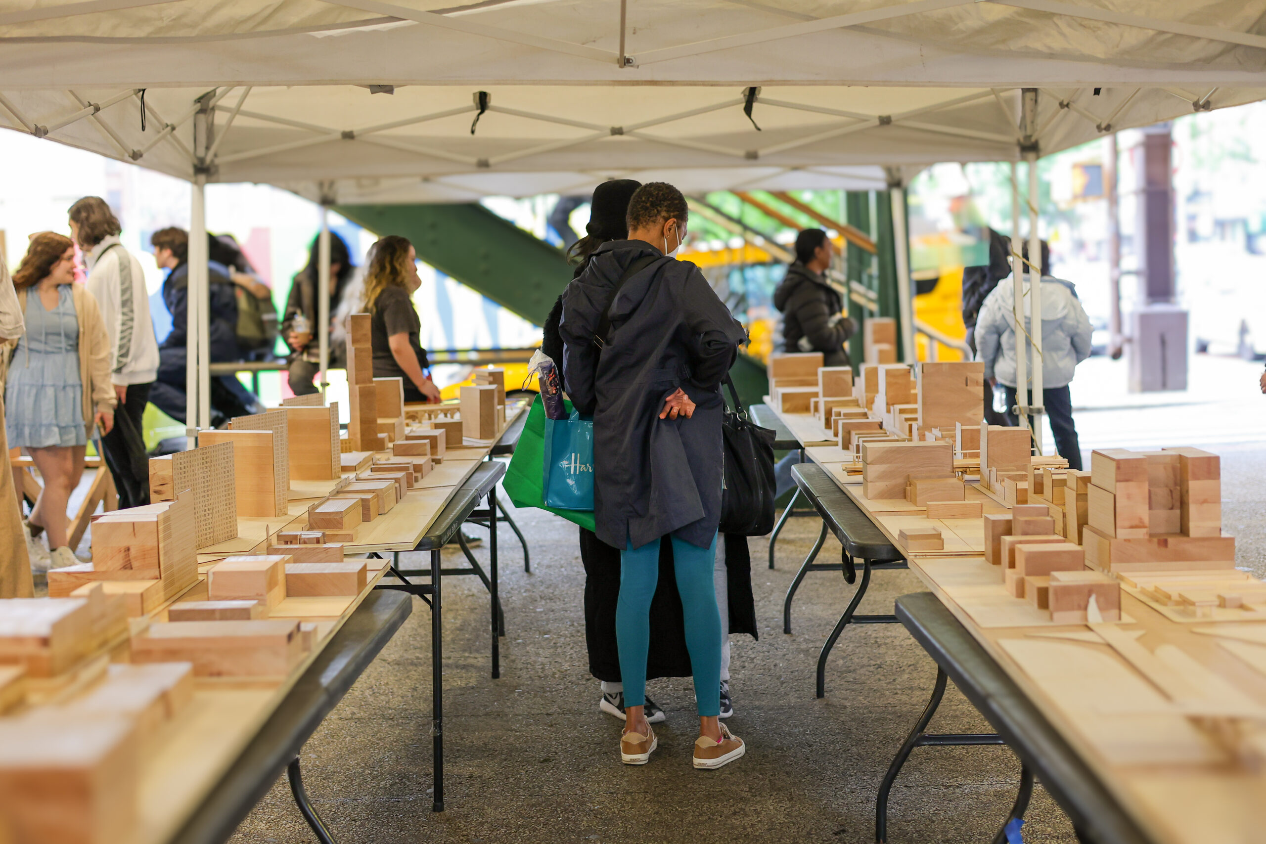 Two people stand between two tables. A wooden model of 125th Street is displayed on both tables.