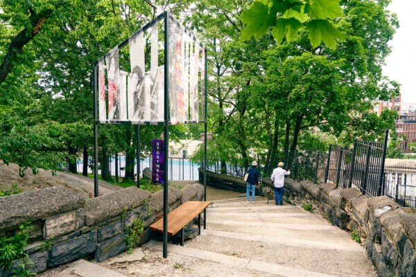 Photograph of the Storywalk installation in Marcus Garvey Park, four metal beams with tapestry attached at the top.