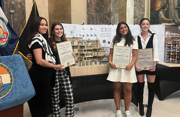 Four B. Arch students standing in front of an architectural model holding award certificate.