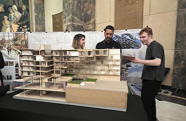 Three people standing behind an architectural model