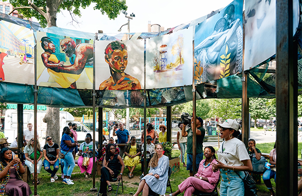 A group of people sitting below the Sankofa installation.