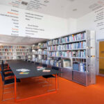 A reading room featuring a red carpet and a table in front of bookshelves.