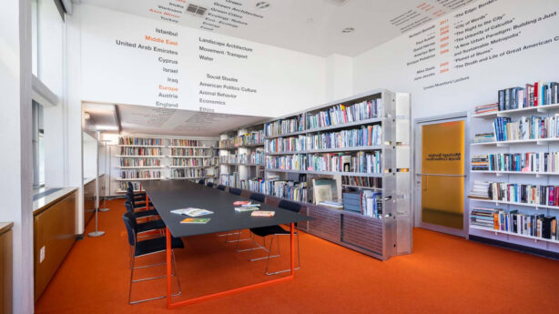 A reading room featuring a red carpet and a table in front of bookshelves.