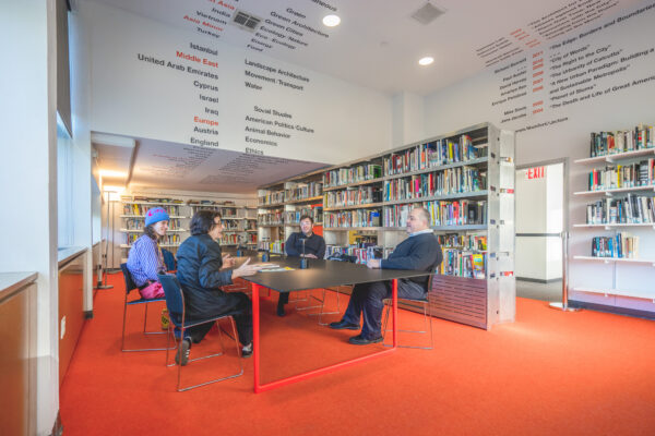 Photograph of four people seated a table talking in the Michael Sorkin Reading Room.