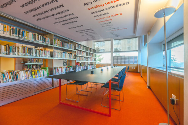 Photograph of a conference table and chairs on orange carpet in the Michael Sorkin Reading Room.