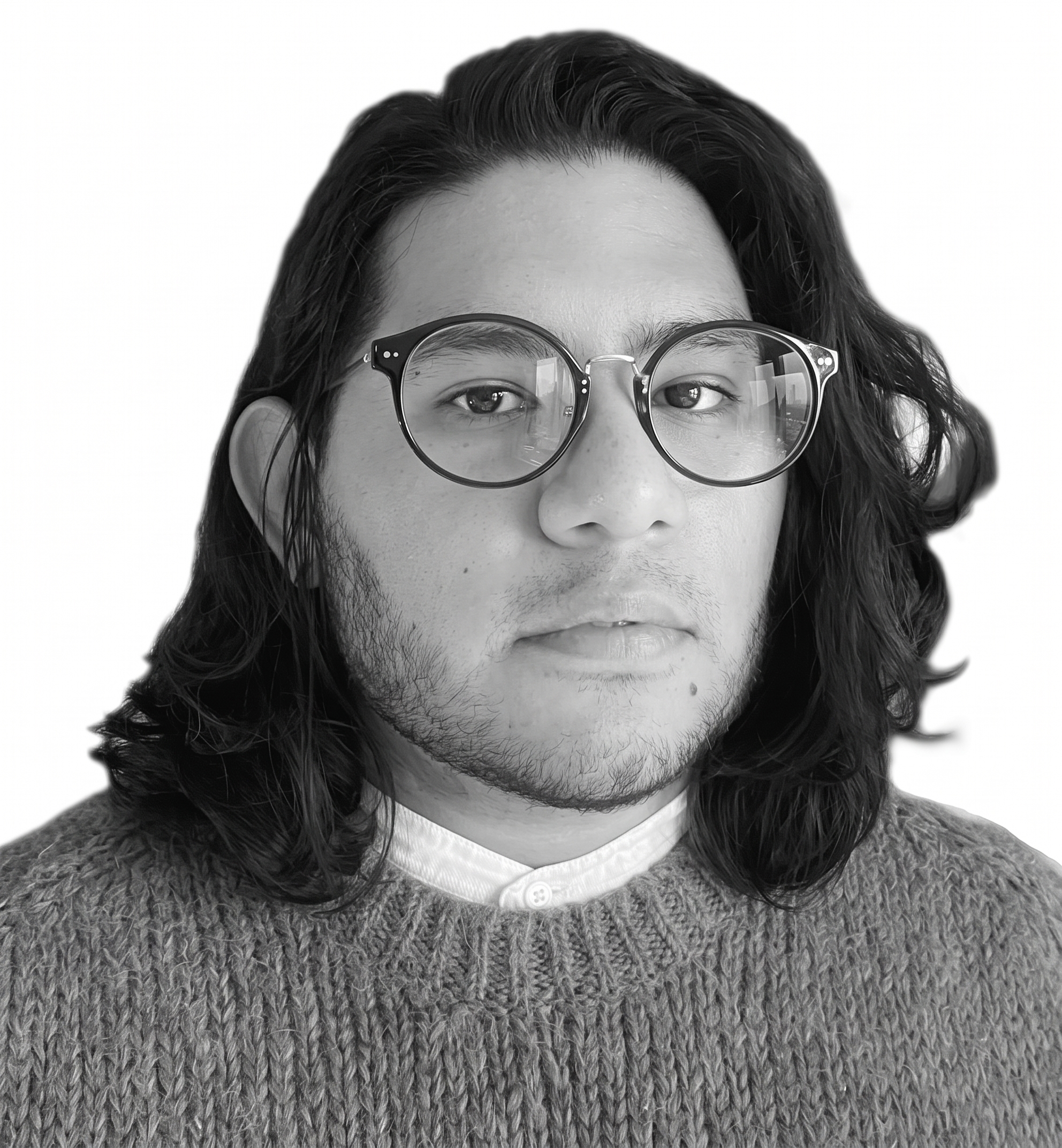 Black and white headshot of Oscar M. Caballero wearing round eyeglasses, a collared shirt under a knit crewneck sweater, with shoulder-length dark hair.